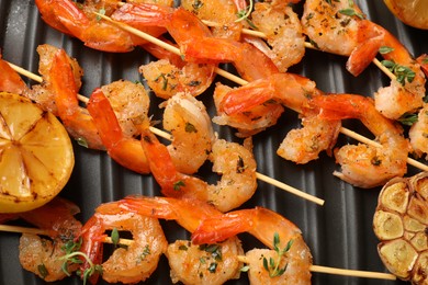 Photo of Skewers with delicious shrimps on grill pan, top view