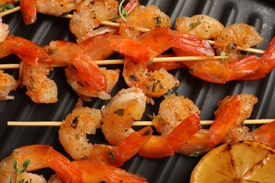 Photo of Skewers with delicious shrimps on grill pan, closeup