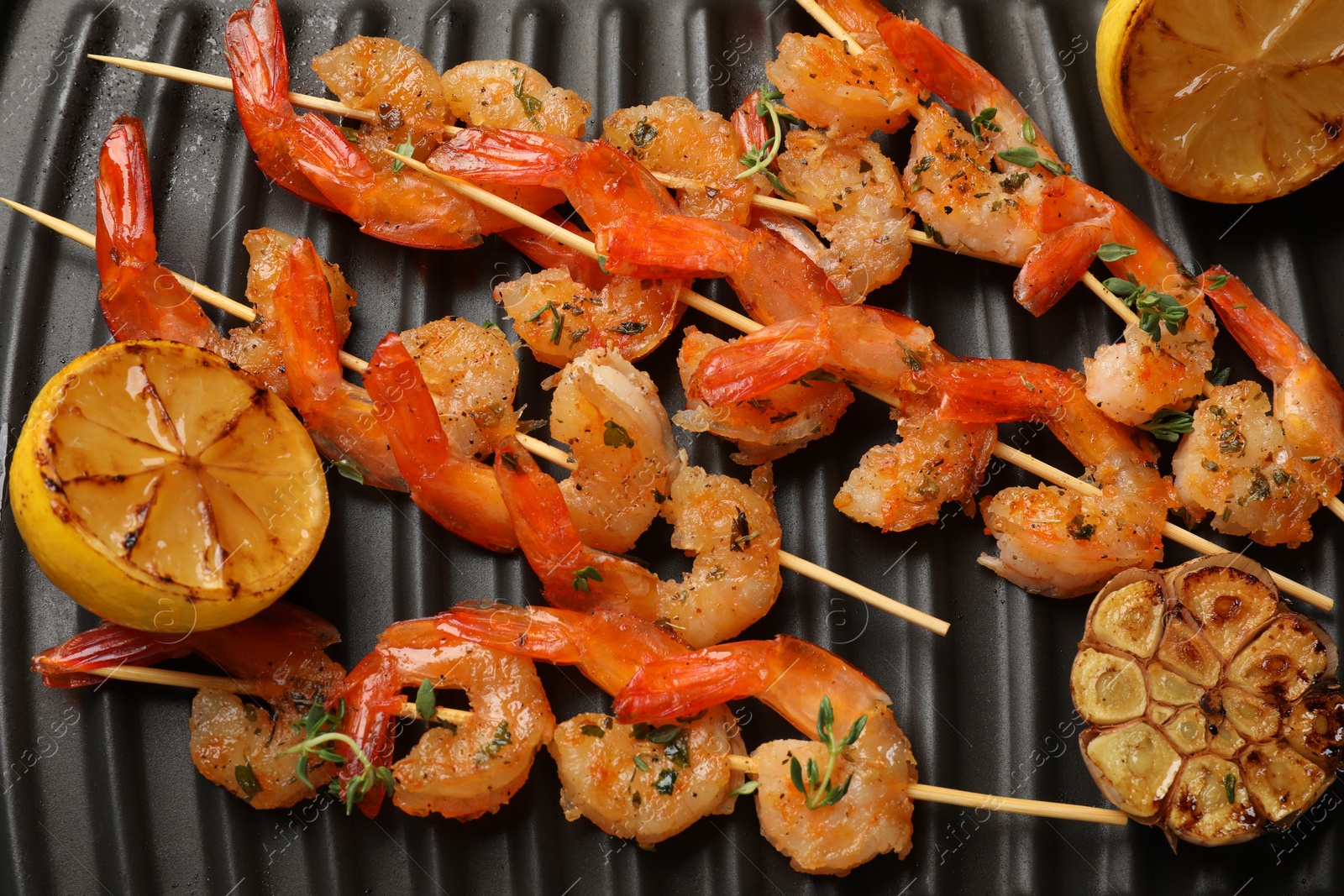 Photo of Skewers with delicious shrimps on grill pan, top view