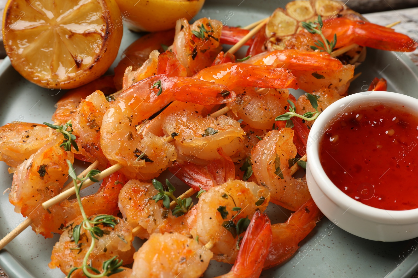 Photo of Delicious grilled shrimp skewers, sauce and lemon on plate, closeup