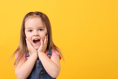 Portrait of emotional little girl on orange background, space for text