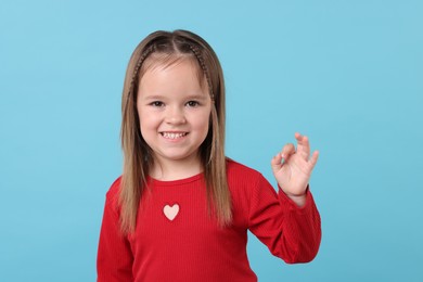 Photo of Portrait of happy little girl on light blue background