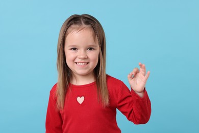 Portrait of happy little girl on light blue background