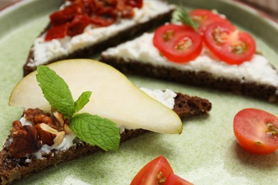 Delicious bruschettas with fresh ricotta (cream cheese), pear and mint on plate, closeup