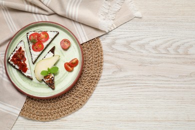 Delicious bruschettas with fresh ricotta (cream cheese) and other products on wooden table, top view. Space for text