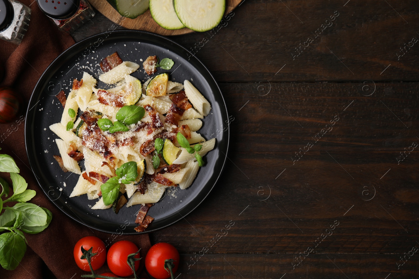 Photo of Tasty pasta with bacon and basil on wooden table, flat lay. Space for text