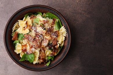 Photo of Tasty pasta with bacon and basil on brown table, top view. Space for text