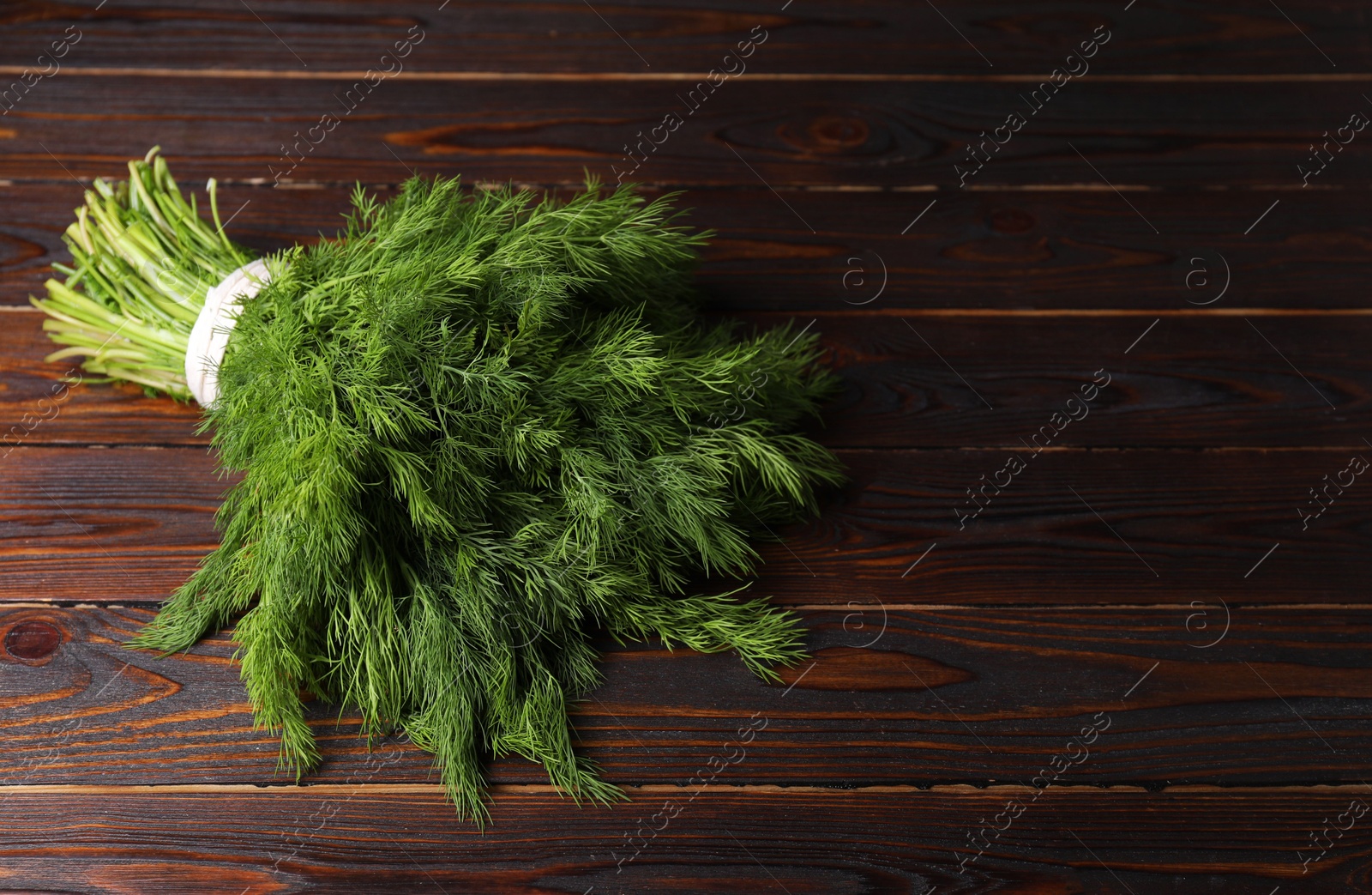 Photo of Bunch of fresh green dill on wooden table, space for text