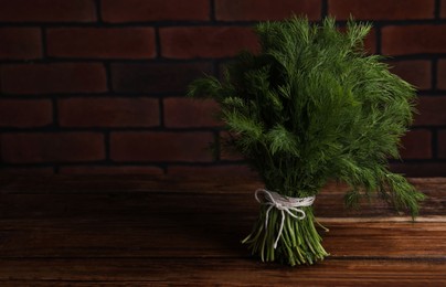 Photo of Bunch of fresh green dill on wooden table, space for text