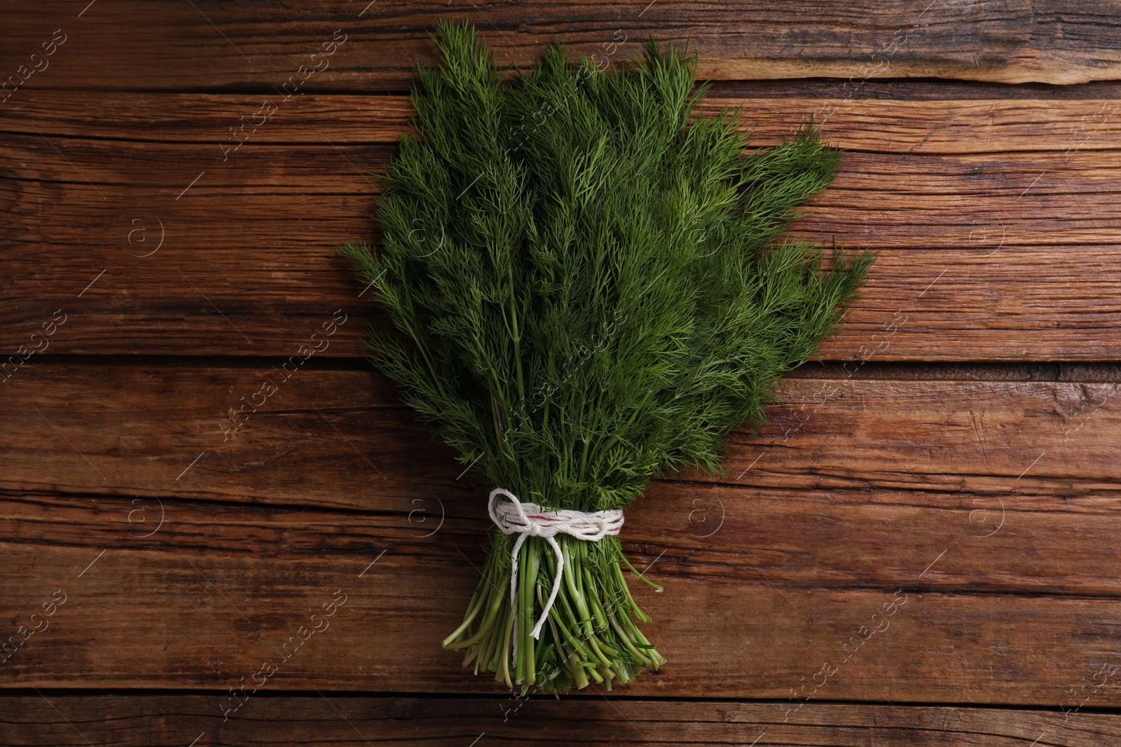 Photo of Bunch of fresh green dill on wooden table, top view