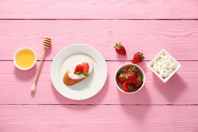 Photo of Delicious ricotta bruschetta with strawberry and mint on pink wooden table, flat lay