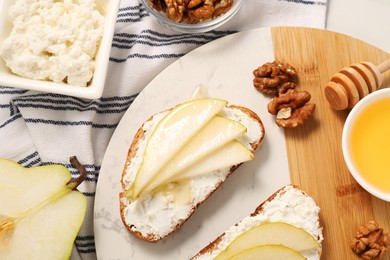 Delicious ricotta bruschettas with pear and walnut on white table, flat lay