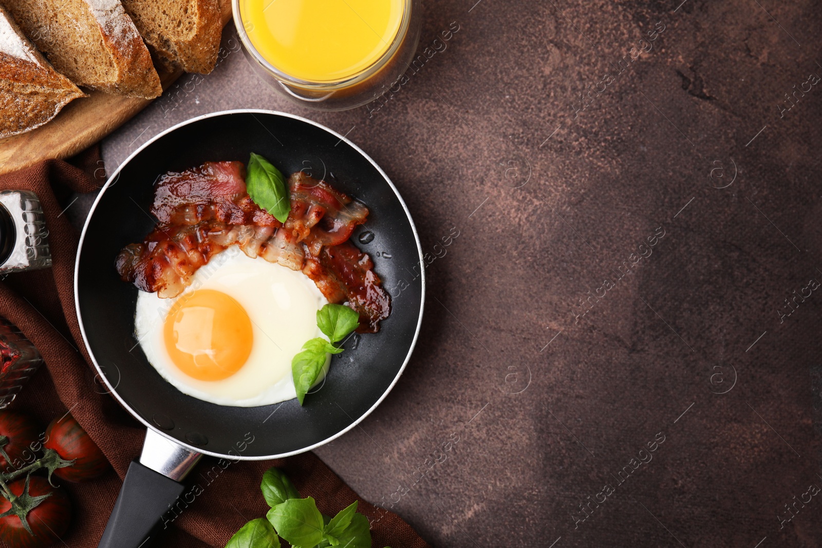 Photo of Fried egg and bacon served on brown table, top view. Space for text