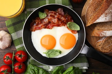 Fried eggs and bacon served on wooden table, top view