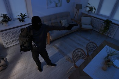 Photo of Thief with gun and jewels in foreign house, above view. Burglary