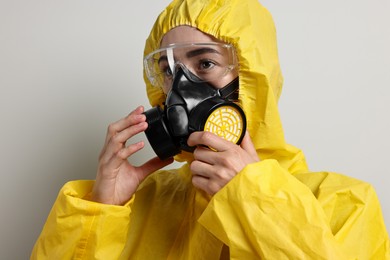 Photo of Worker in respirator, protective suit and glasses on grey background