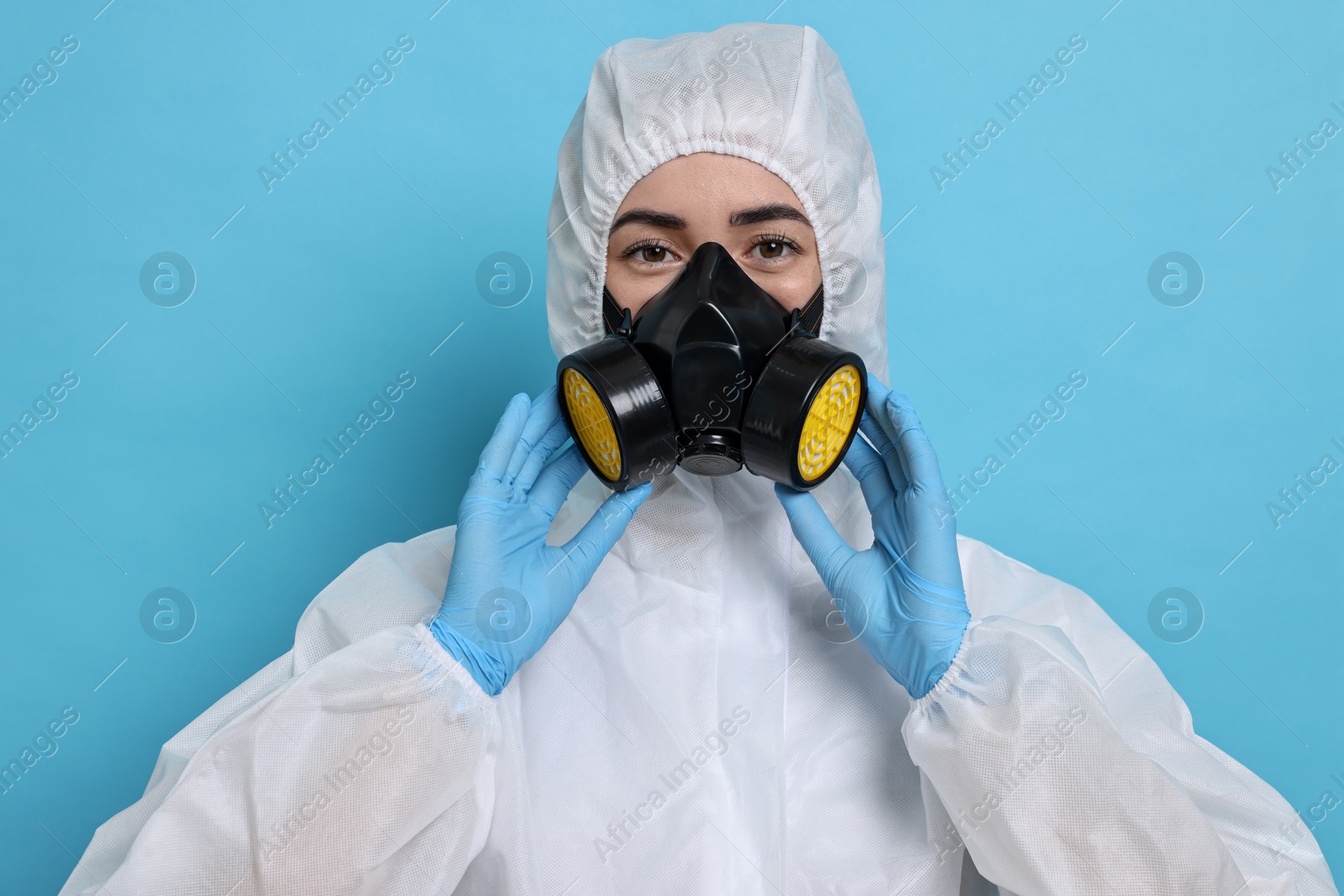 Photo of Worker in respirator and protective suit on light blue background