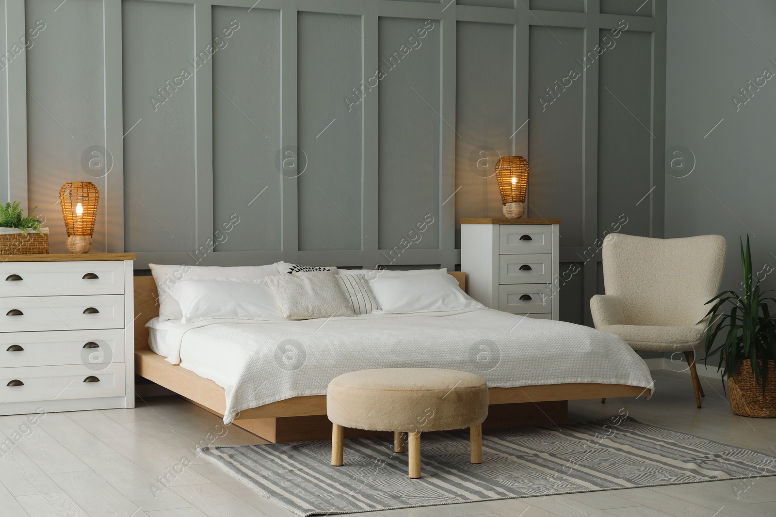 Photo of Stylish bedroom interior with comfortable bed, lamps, armchair and houseplant