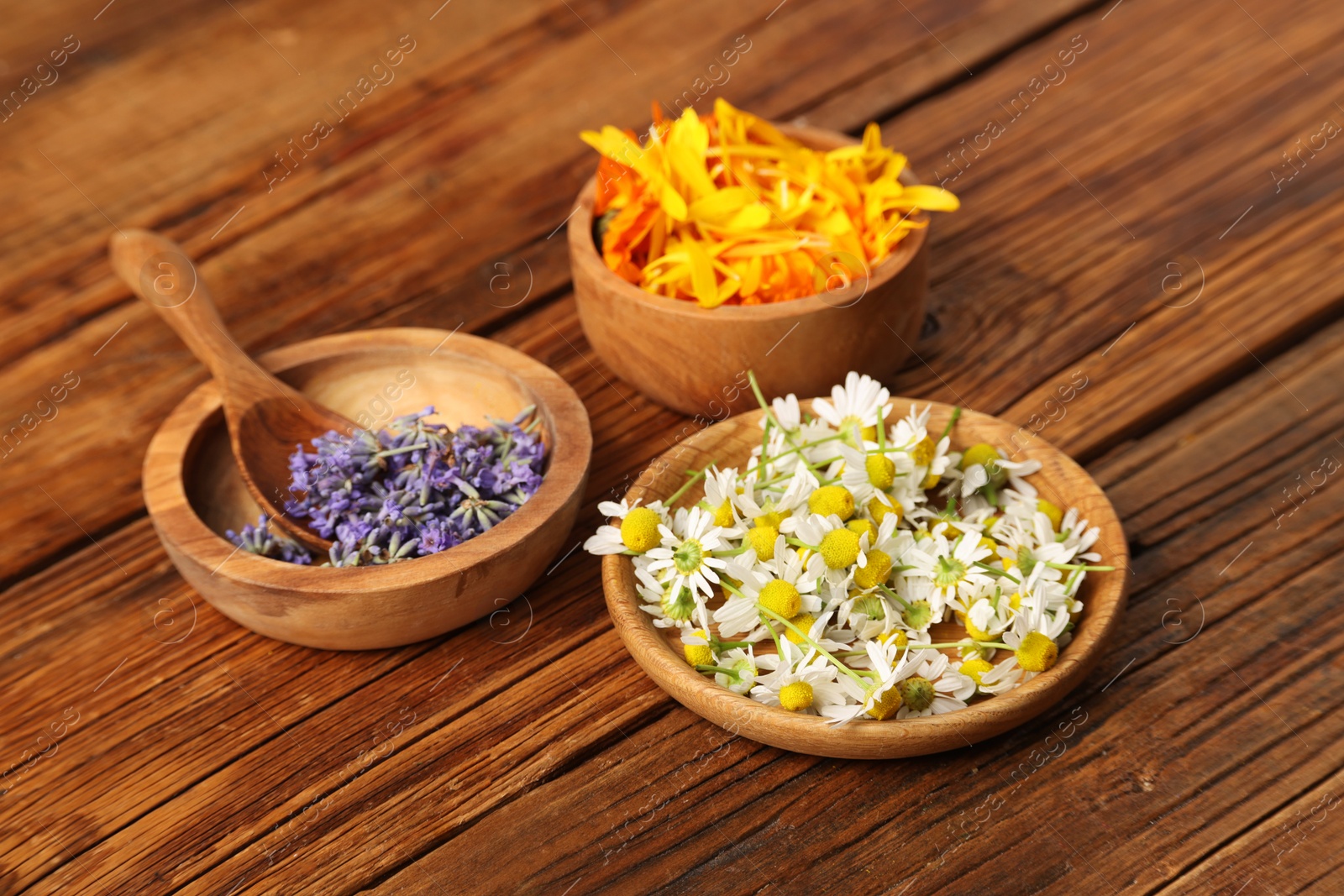 Photo of Different flowers in bowls and spoon on wooden table