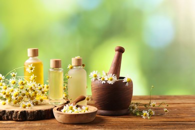 Different flowers and bottles of essential oils on wooden table, space for text