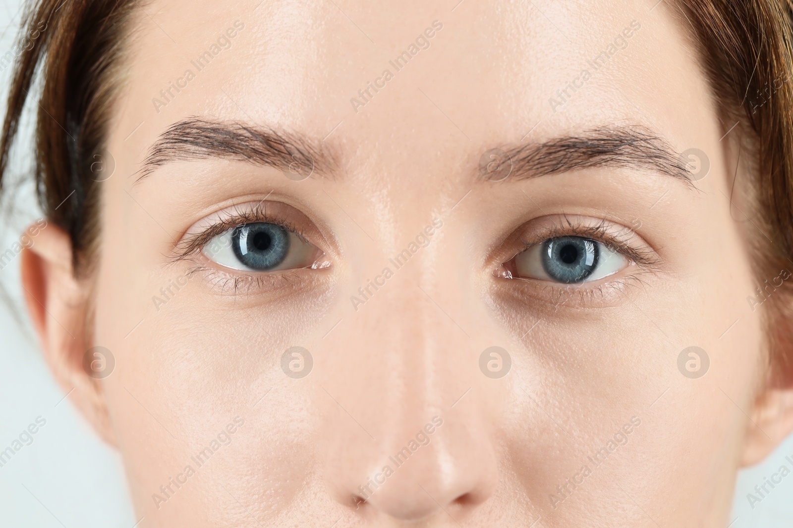 Photo of Woman with beautiful blue eyes on light background, closeup