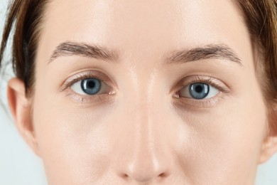 Woman with beautiful blue eyes on light background, closeup