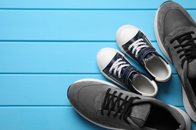 Photo of Big and small shoes on light blue wooden table, top view. Space for text