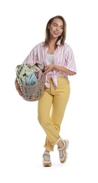 Happy young housewife with basket full of laundry on white background