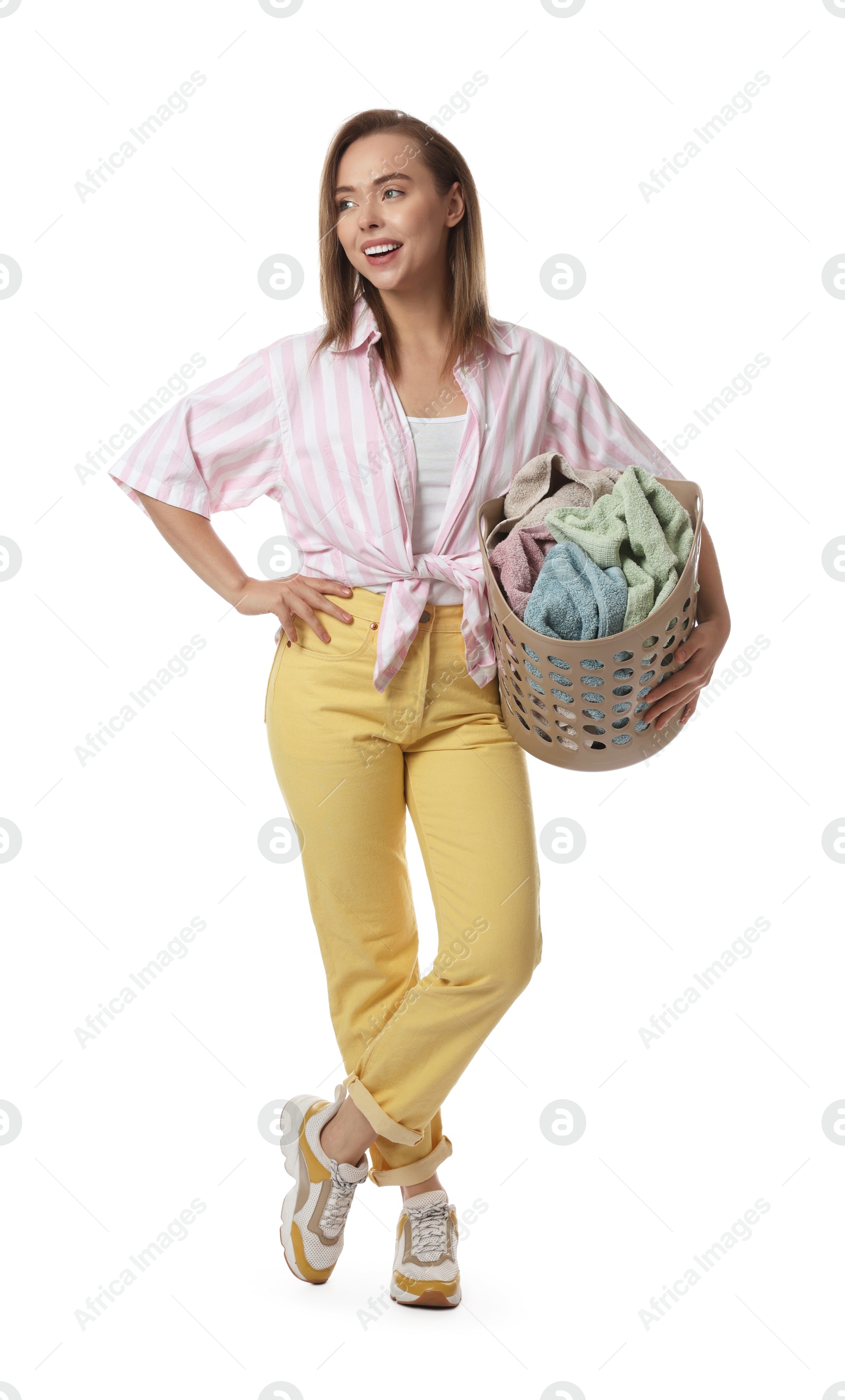 Photo of Happy young housewife with basket full of laundry on white background