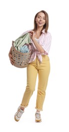 Happy young housewife with basket full of laundry on white background