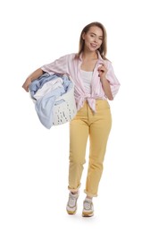 Happy young housewife with basket full of laundry on white background