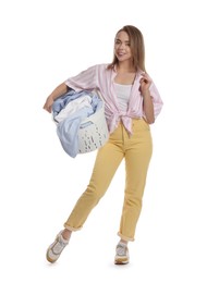 Happy young housewife with basket full of laundry on white background