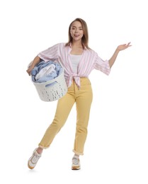 Happy young housewife with basket full of laundry on white background