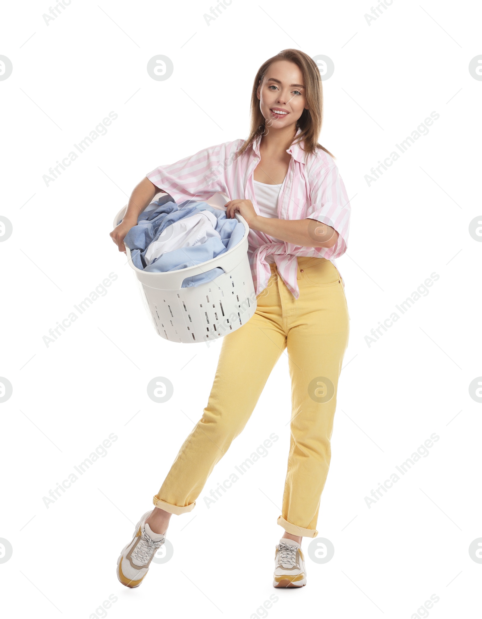 Photo of Happy young housewife with basket full of laundry on white background