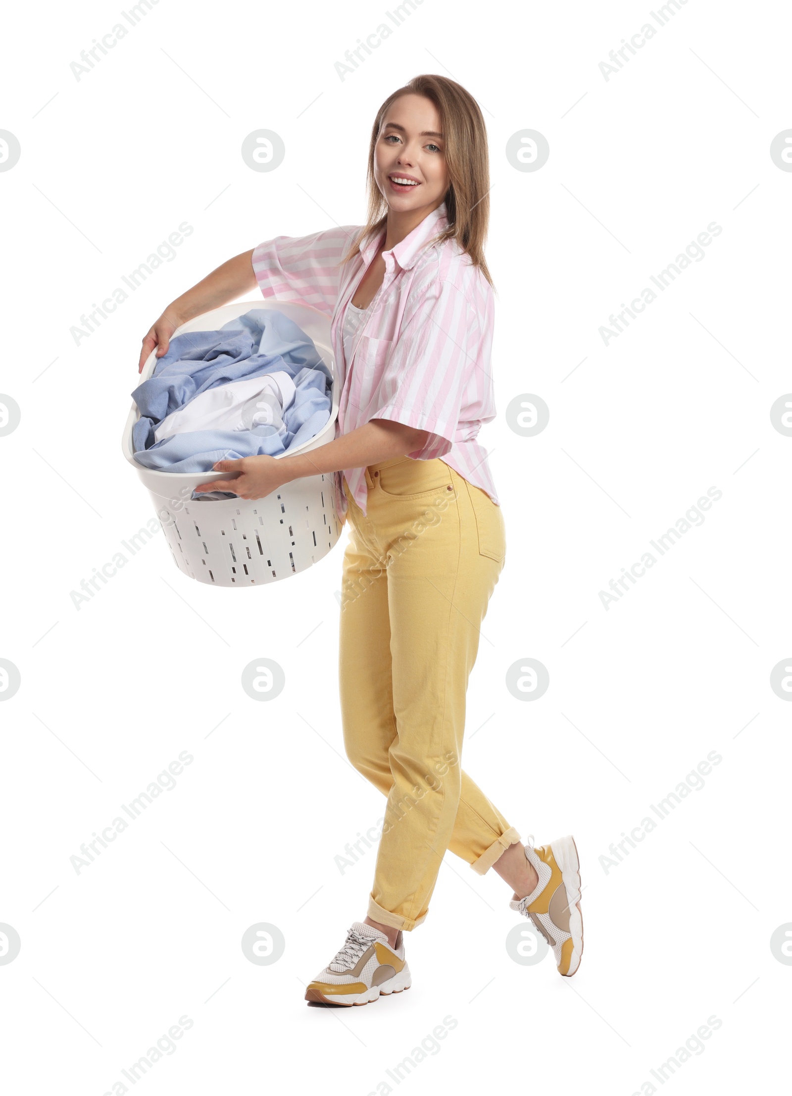 Photo of Happy young housewife with basket full of laundry on white background