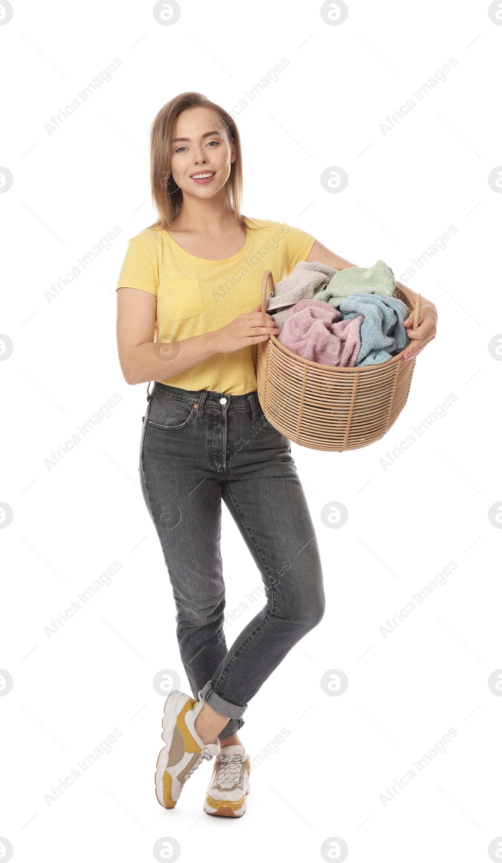 Photo of Happy young housewife with basket full of laundry on white background