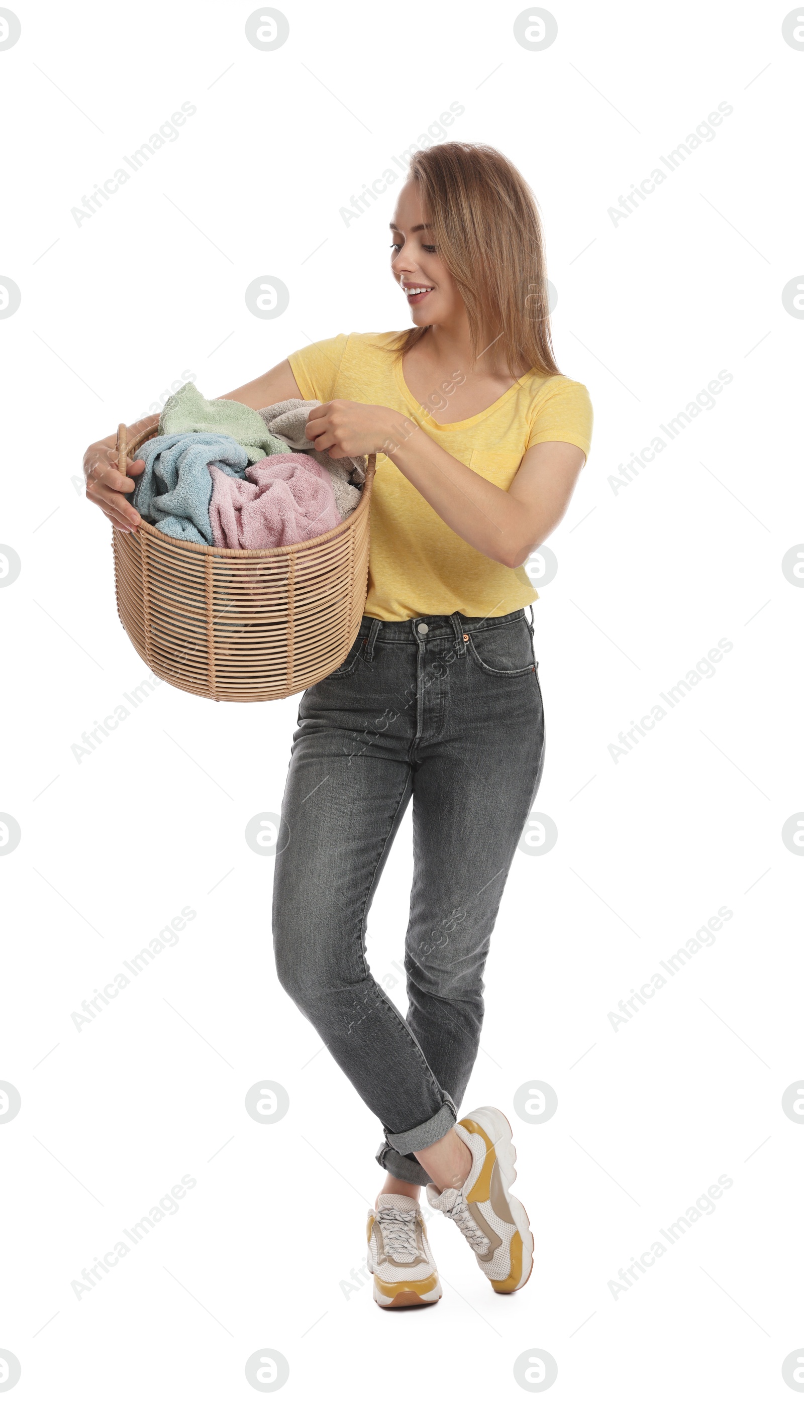 Photo of Happy young housewife with basket full of laundry on white background