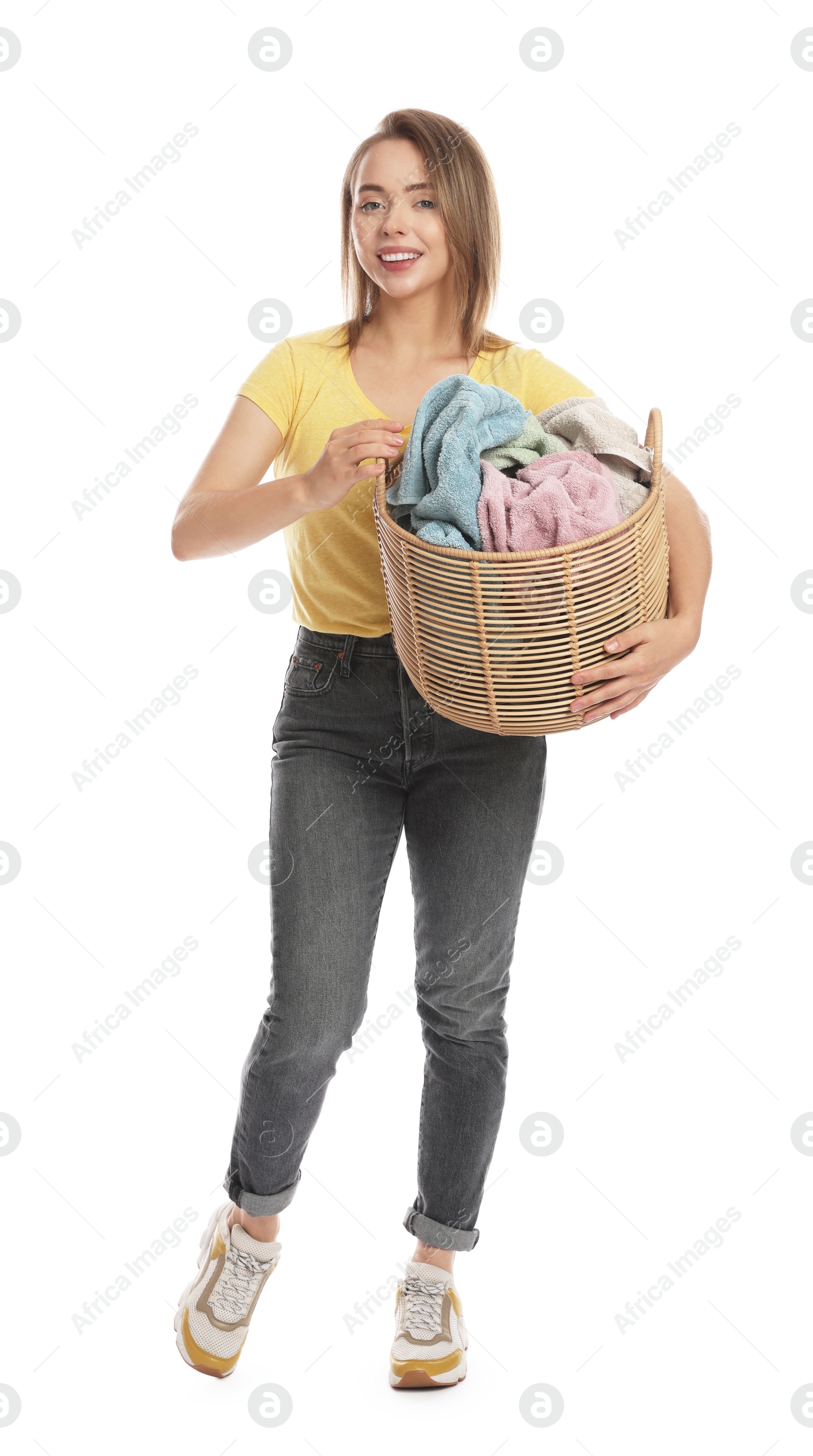 Photo of Happy young housewife with basket full of laundry on white background