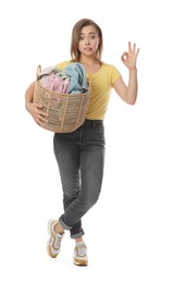 Young housewife with basket full of laundry on white background