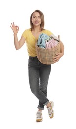 Photo of Happy young housewife with basket full of laundry on white background