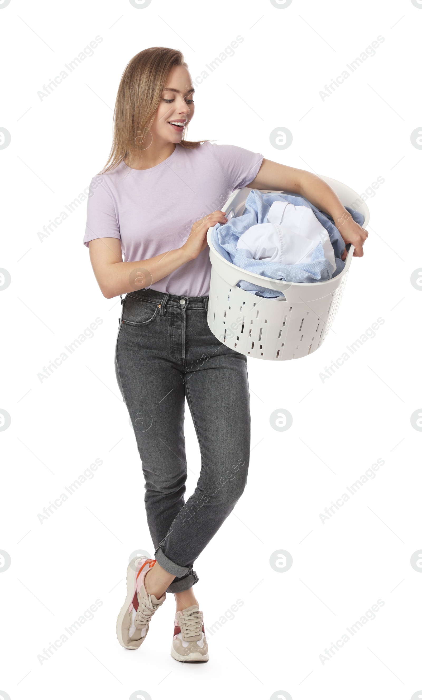 Photo of Happy young housewife with basket full of laundry on white background