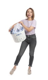 Happy young housewife with basket full of laundry on white background