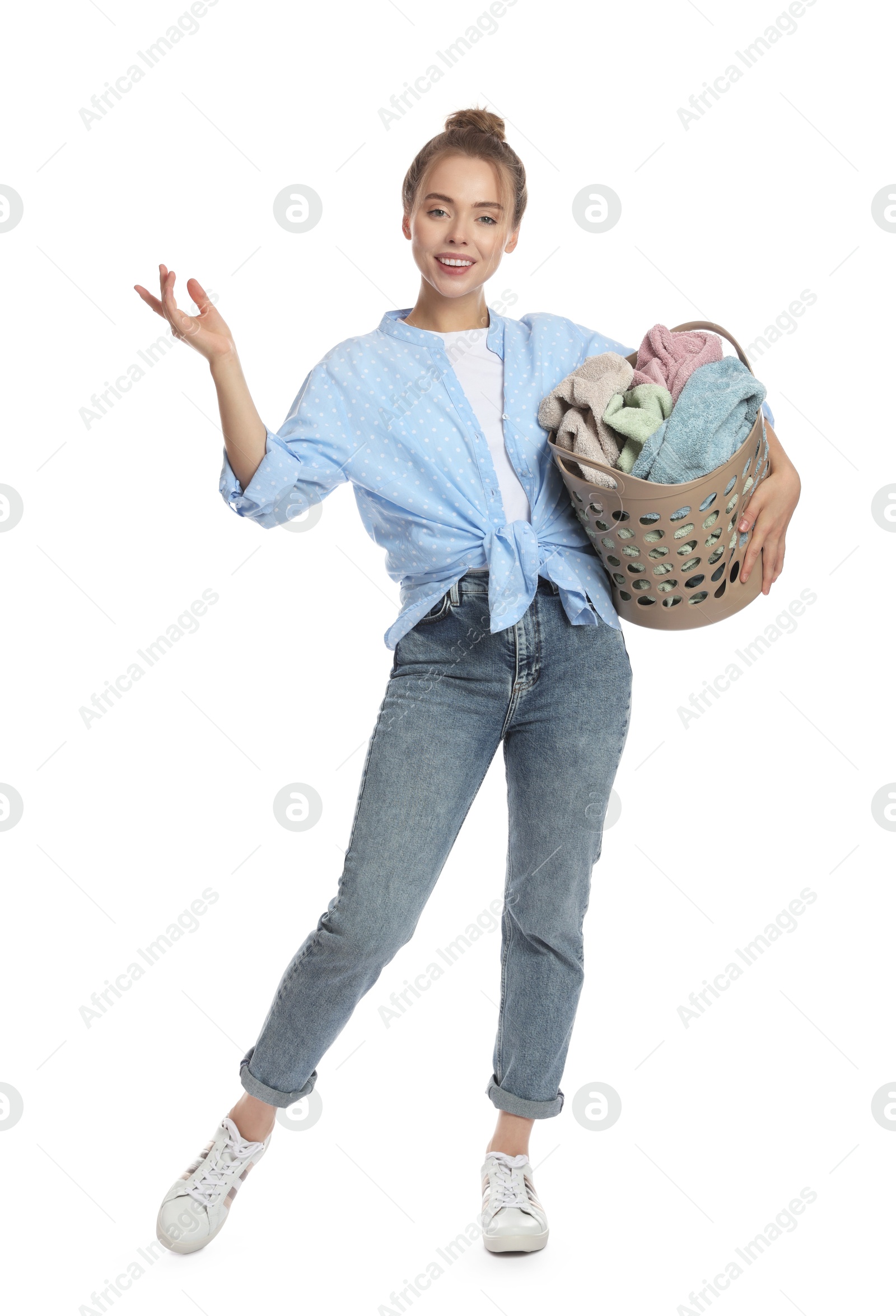 Photo of Happy young housewife with basket full of laundry on white background