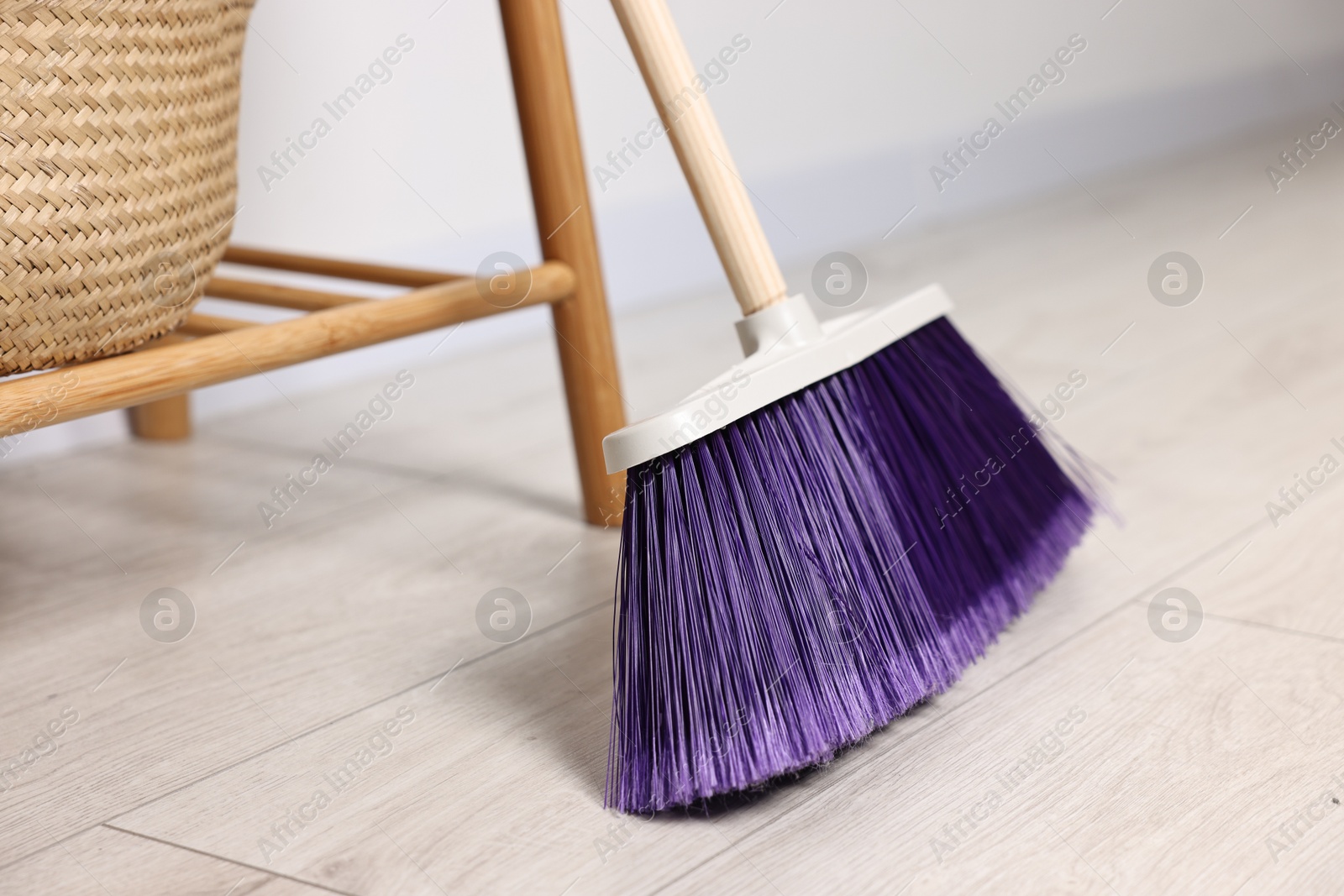 Photo of Sweeping wooden floor with bright broom indoors