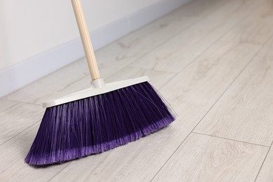 Photo of Sweeping wooden floor with bright broom indoors, space for text