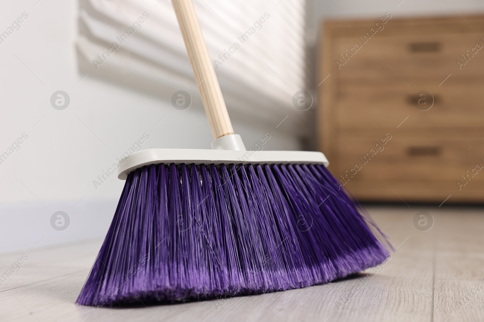 Photo of Sweeping wooden floor with bright broom indoors