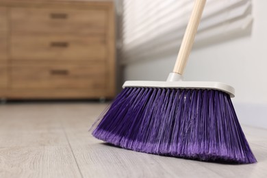 Photo of Sweeping wooden floor with bright broom indoors