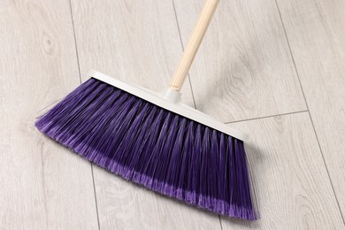 Photo of Sweeping wooden floor with bright broom indoors, top view