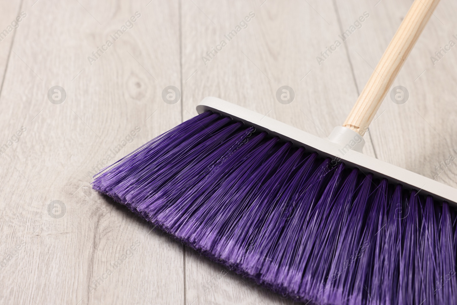 Photo of Sweeping wooden floor with bright broom indoors