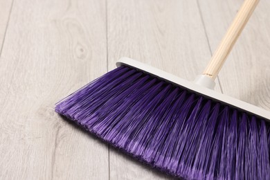 Photo of Sweeping wooden floor with bright broom indoors